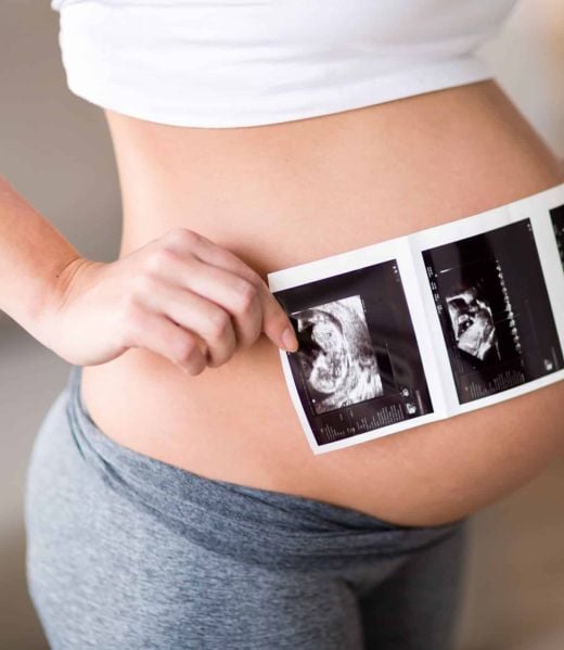 Pregnant woman holding ultrasound photo on her belly